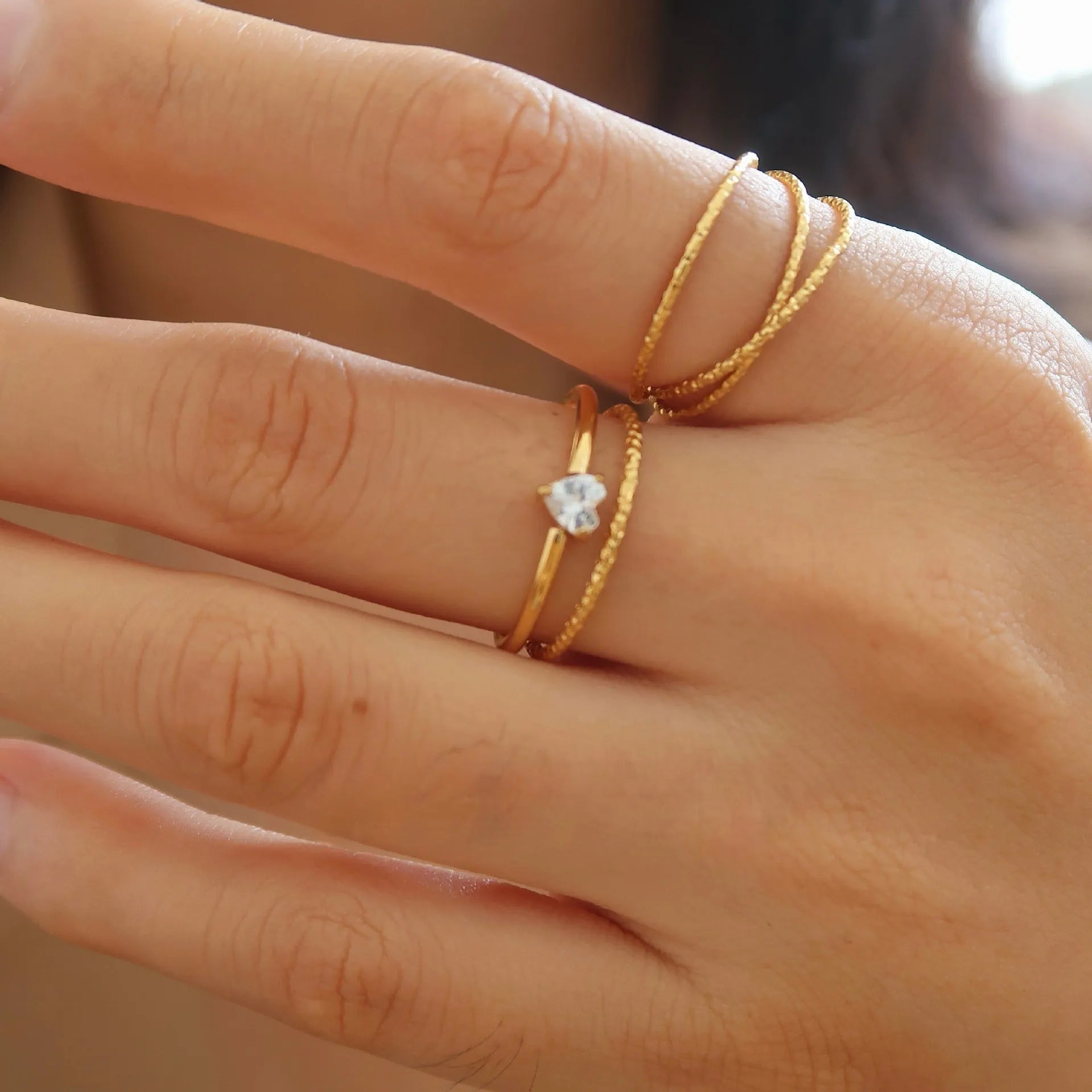 Gold heart-shaped ring and gold oval ring on display, both in stainless steel for women.