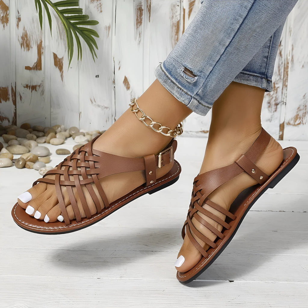 Flat buckle open toe Roman style beach slippers in black shown on a light background.