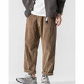 Man wearing loose straight leg casual trousers in dark grey, showing tapered fit and wide leg opening.