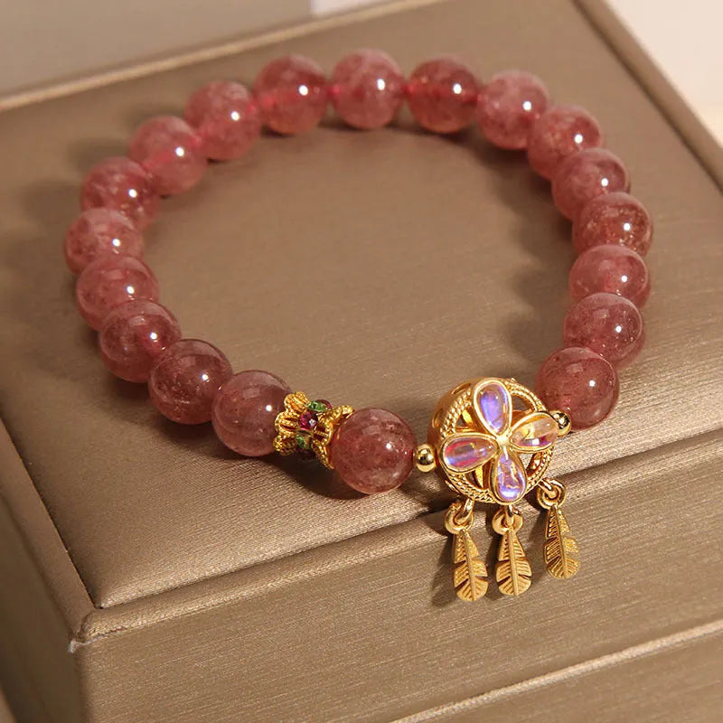 Women's strawberry quartz dream catcher ball pendant bracelet on wrist.