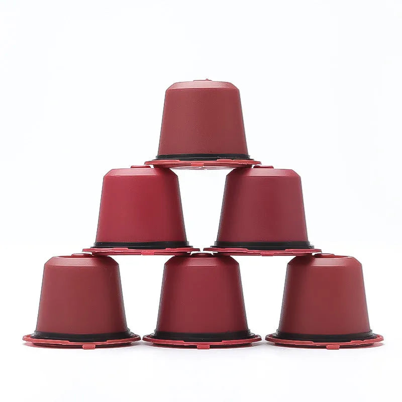 Set of six recyclable reusable plastic coffee filter cups in black, brown, and red with a spoon on wooden background