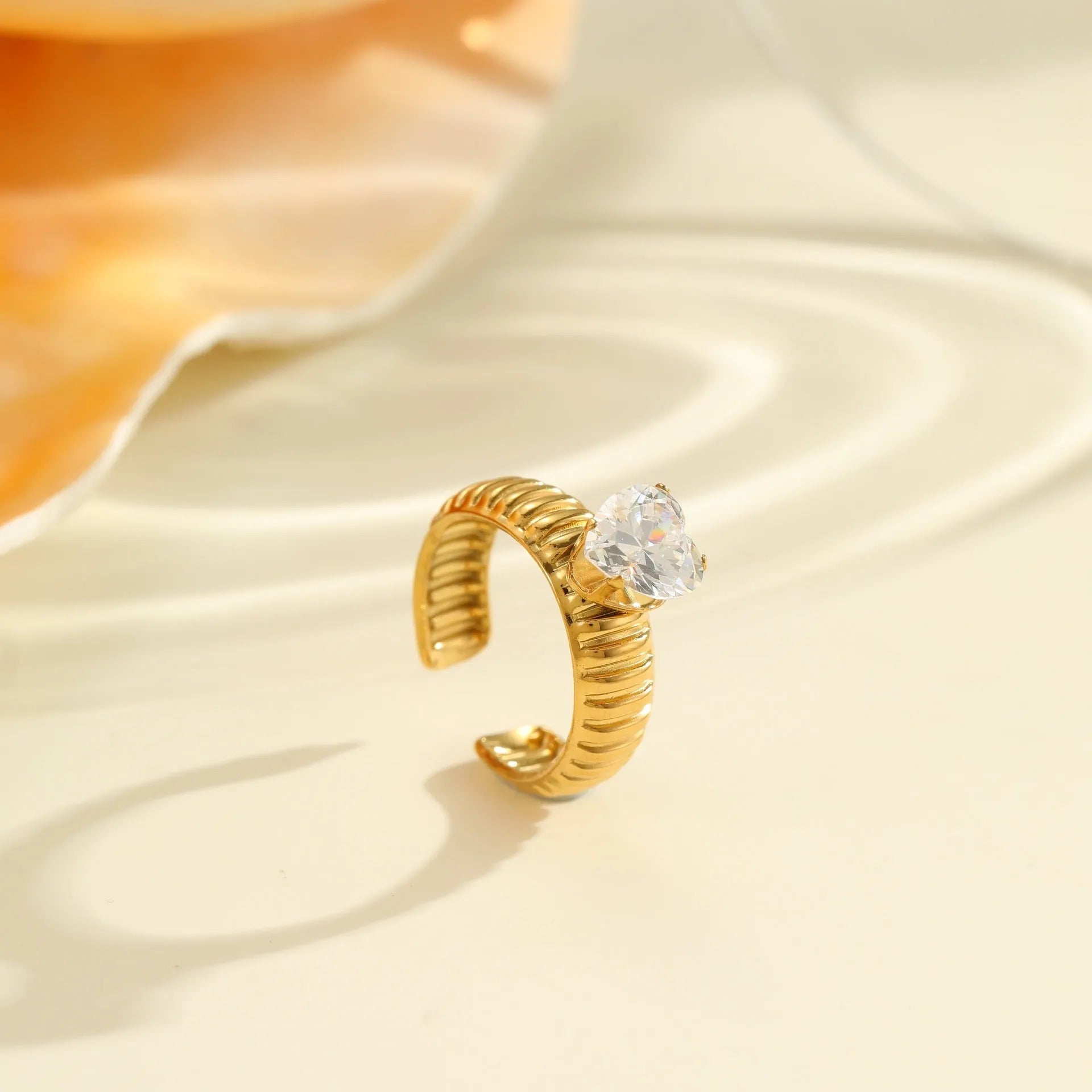 Gold colour stainless steel ring with zircon stones in a geometric heart drop shape design, open mouth.