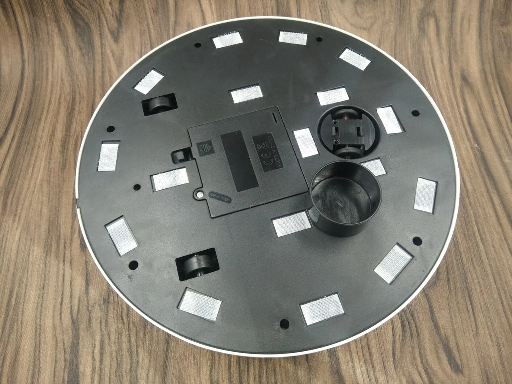 Black and white automatic robot vacuum cleaner on a wooden floor.