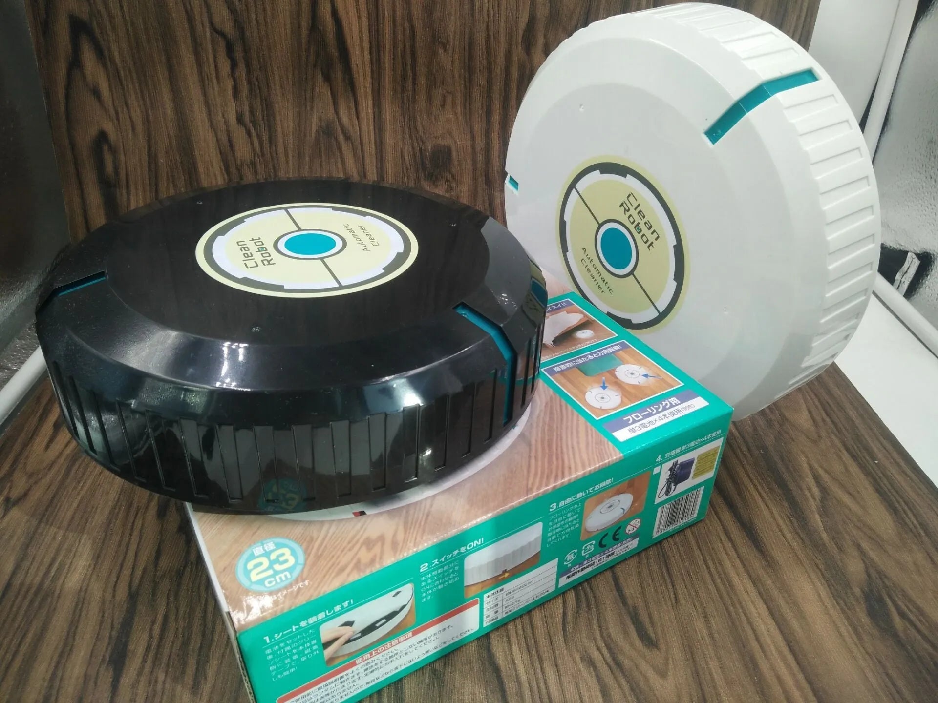 Black and white automatic robot vacuum cleaner on a wooden floor.