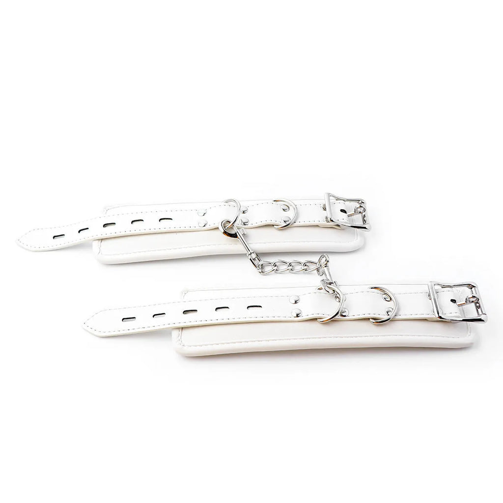 White PU sponge bondage set showing handcuffs, footcuffs, and a neck cuff laid out on a dark surface.