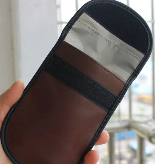 Black plain microfiber faraday cage bag for blocking RFID and phone signals, shown with a key fob inside.