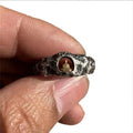 Close-up of a hand-forged copper ring with a Grotto Buddha design and rock texture.