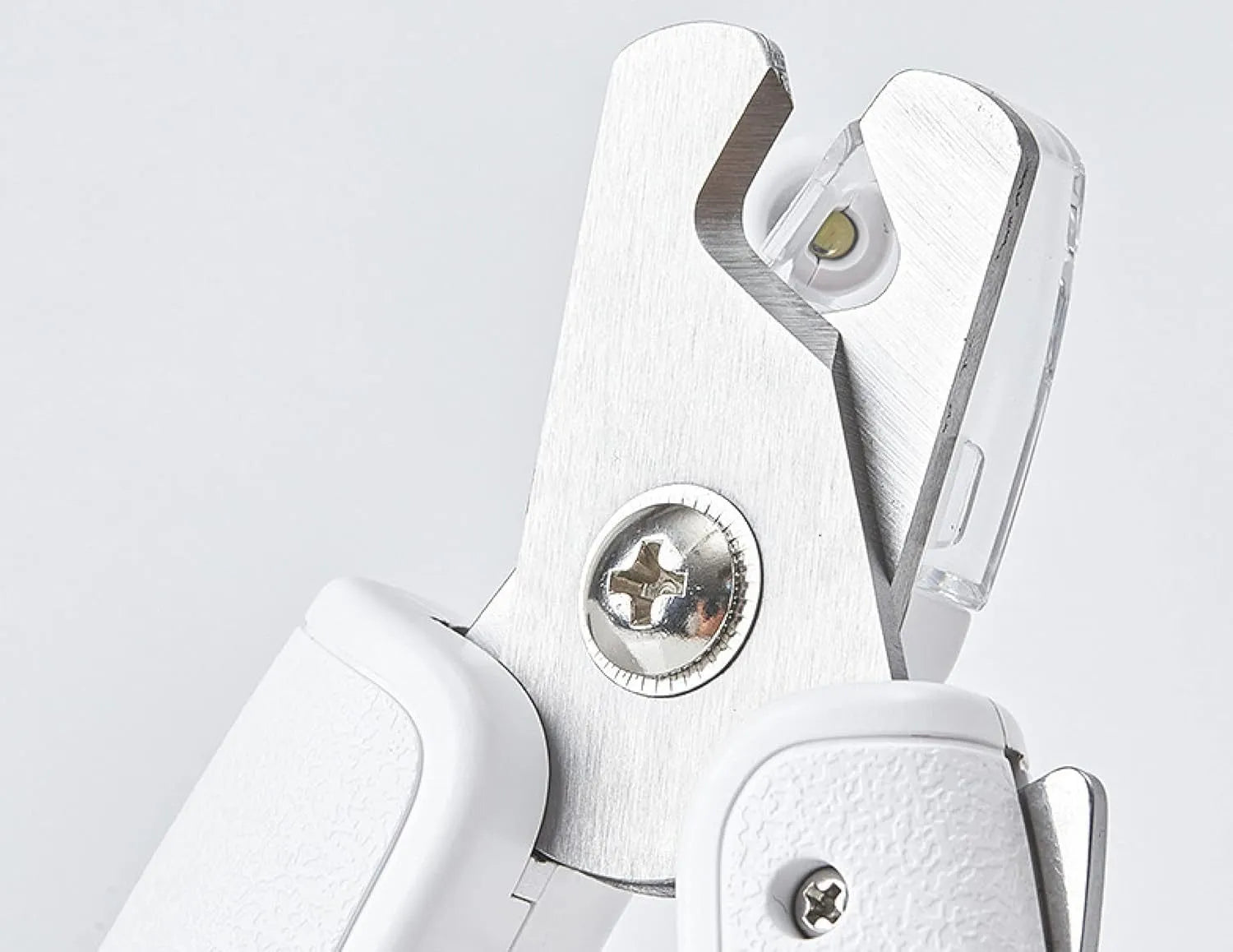 White pet nail clippers with LED light and transparent guard, shown with a separate nail file on a table.