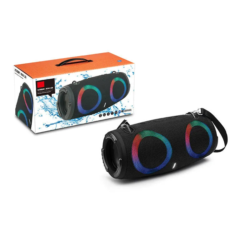 War Drum portable Bluetooth speaker with glowing RGB light ring in camouflage colour, sitting on grass.