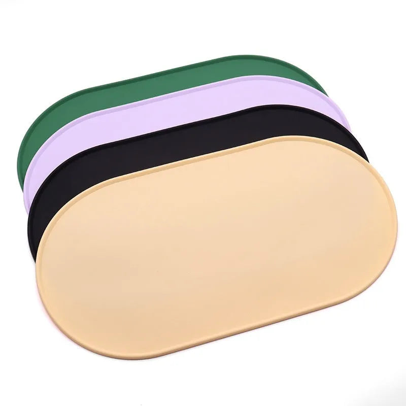 Green silicone cat feeding mat with raised edges containing dry kibble, placed on a wooden floor.
