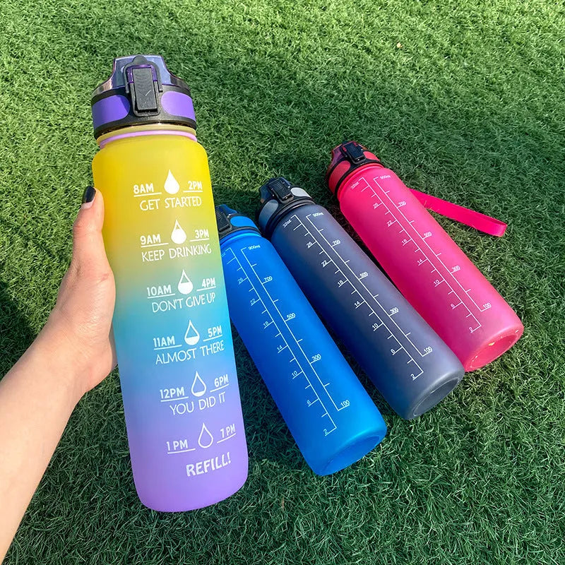 Blue-red gradient 1L Tritan water bottle with time markers and flip-top lid on a gym bag