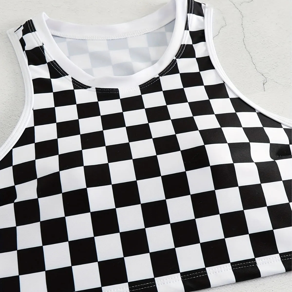 Women's backless one-piece swimsuit with black and white chessboard pattern and sporty suspender straps.