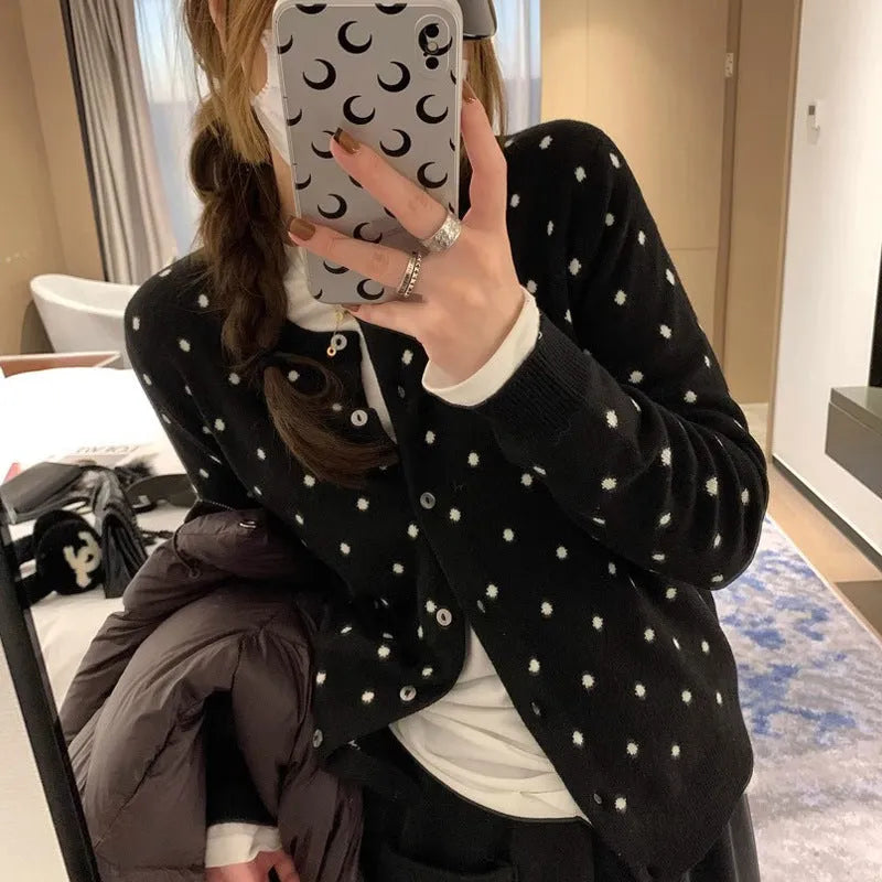 Grey dot pattern women's knitted cardigan with crochet flower detail on a hanger.