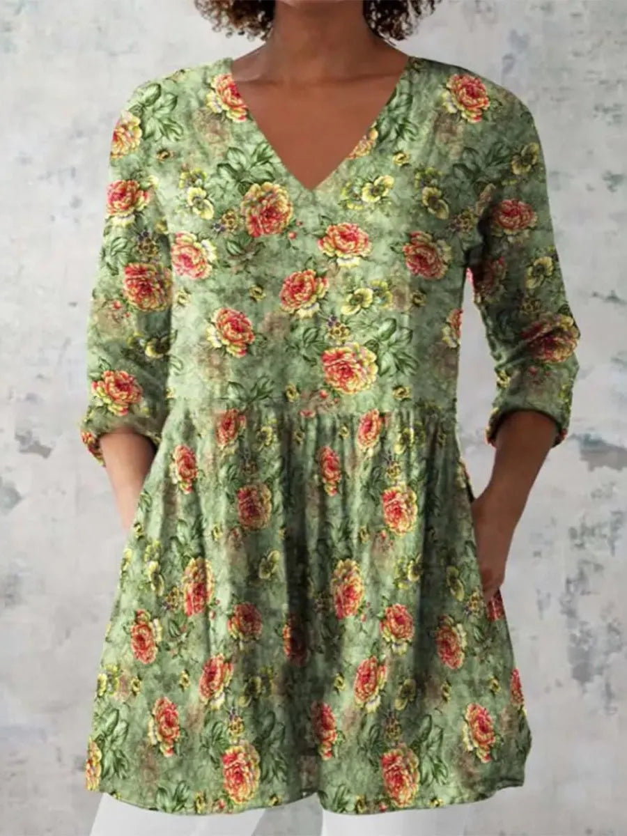 A woman wearing a loose-fitting blue dress with a white wave print, featuring three-quarter sleeves and a wide waist.