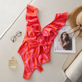 Women's printed one-piece swimsuit with double shoulder straps and ruffled mesh detail on a deep V-neck.
