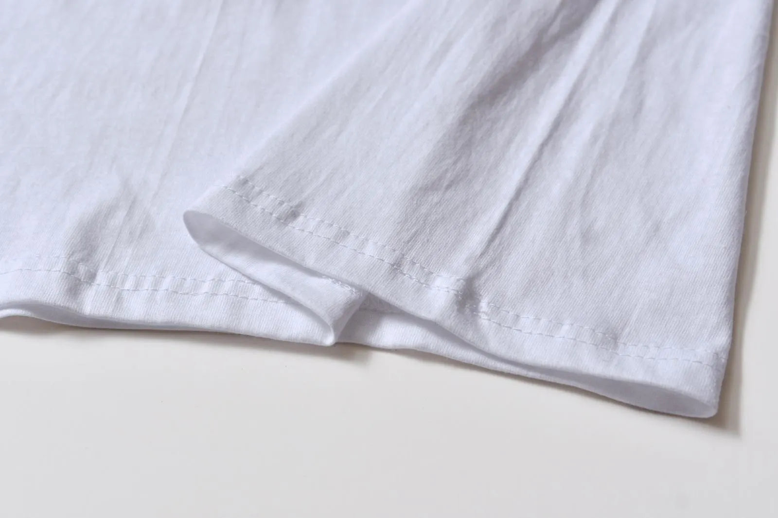 White cotton pullover overalls with short sleeves and a round neck, shown on a hanger.