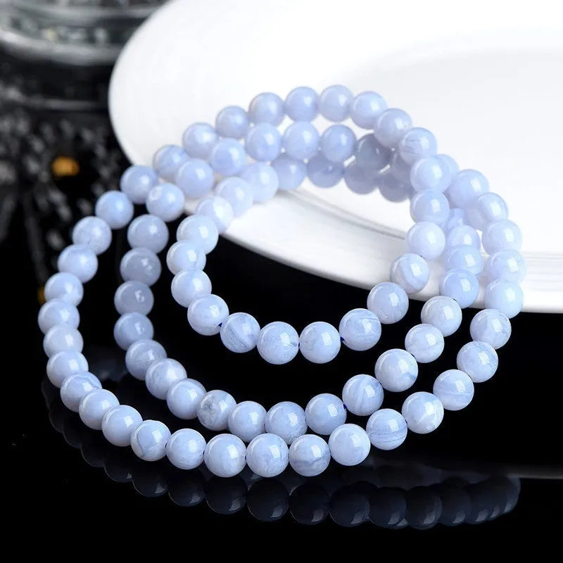 Close-up of a blue striped agate beaded bracelet with Ruyi design on a neutral background.