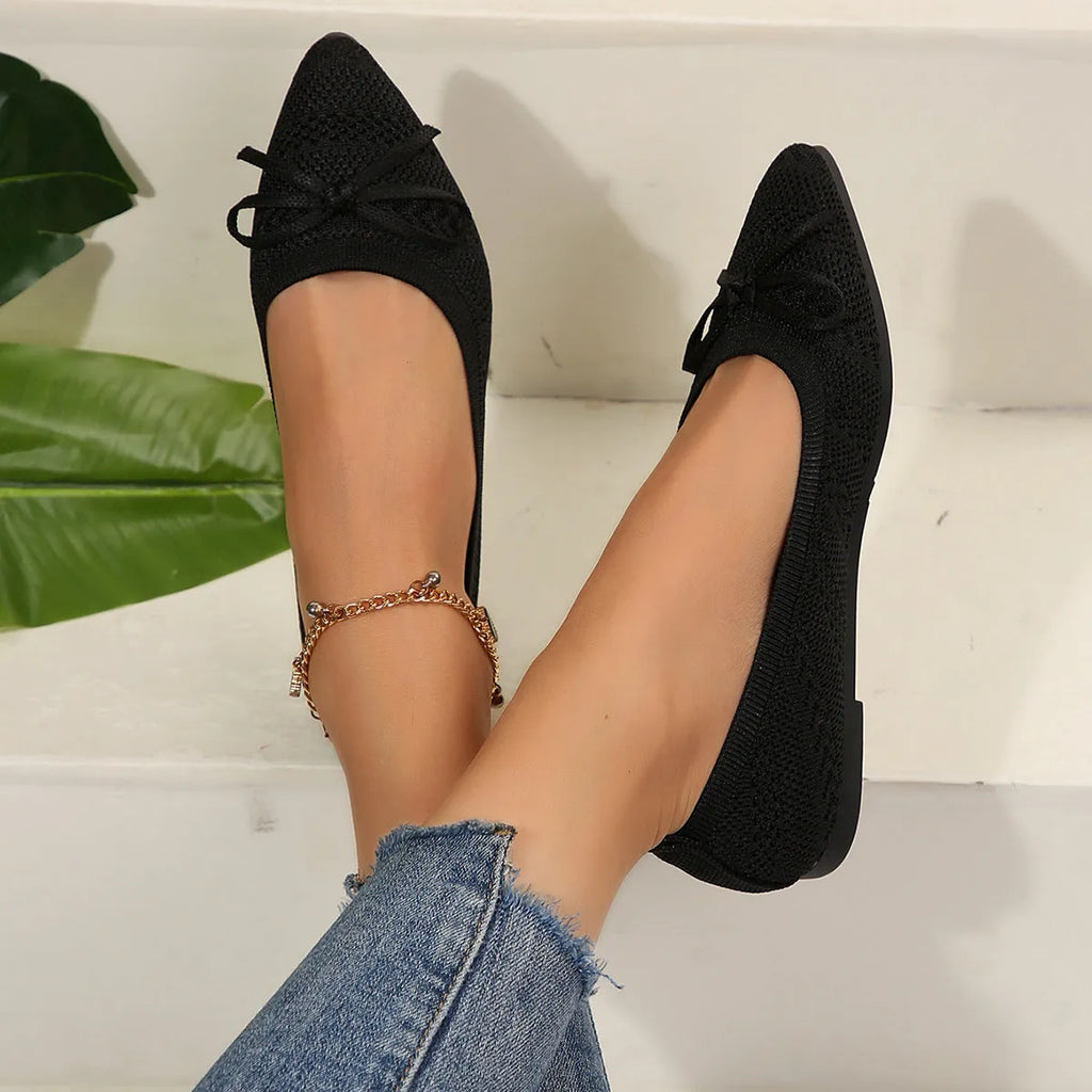 Women's blue knitted loafers with a bow detail and pointed toe on a flat rubber sole.