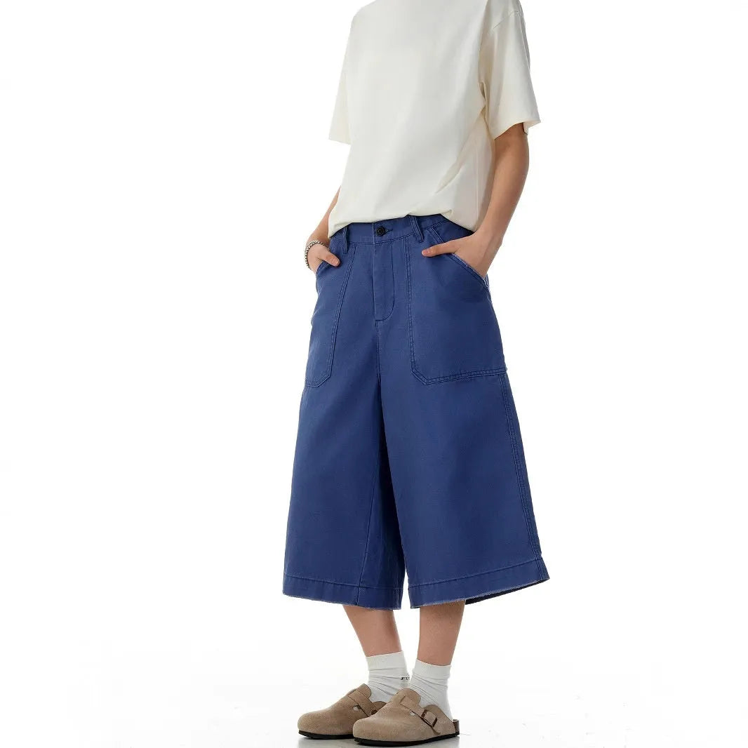 Men's French blue cotton shorts, loose straight-leg fit, mid-rise waist with zipper fly, lying flat.