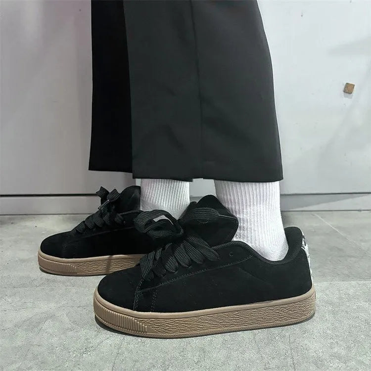 Black retro low-top sneakers with round toe and front lace-up closure on injection-moulded rubber sole