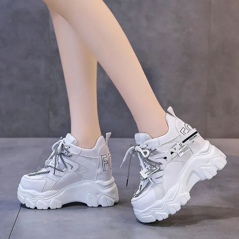 White women's low-top platform sports trainers with mesh panels and a black cross-strap on a rubber sole.