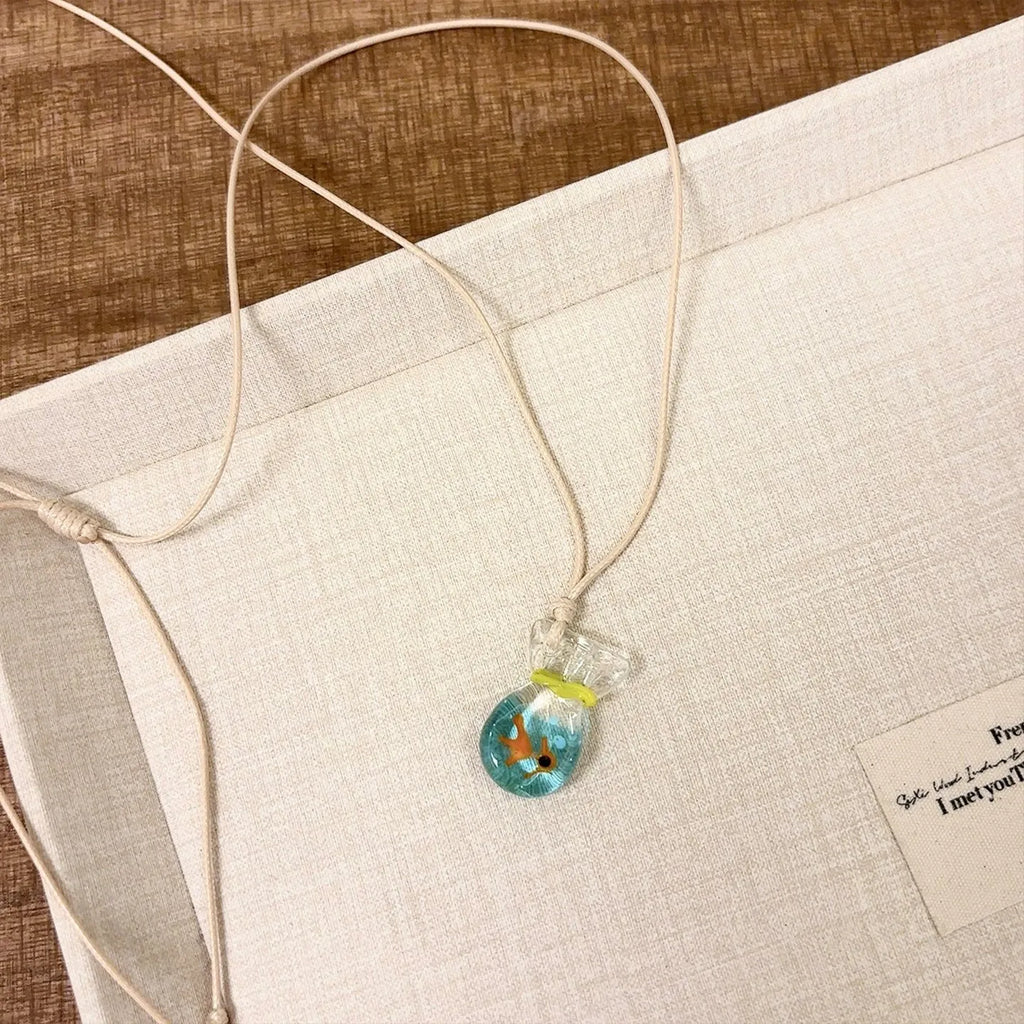 Women's coloured glaze pendant necklace on a braided cotton and linen clavicle chain, showing artisan finish.