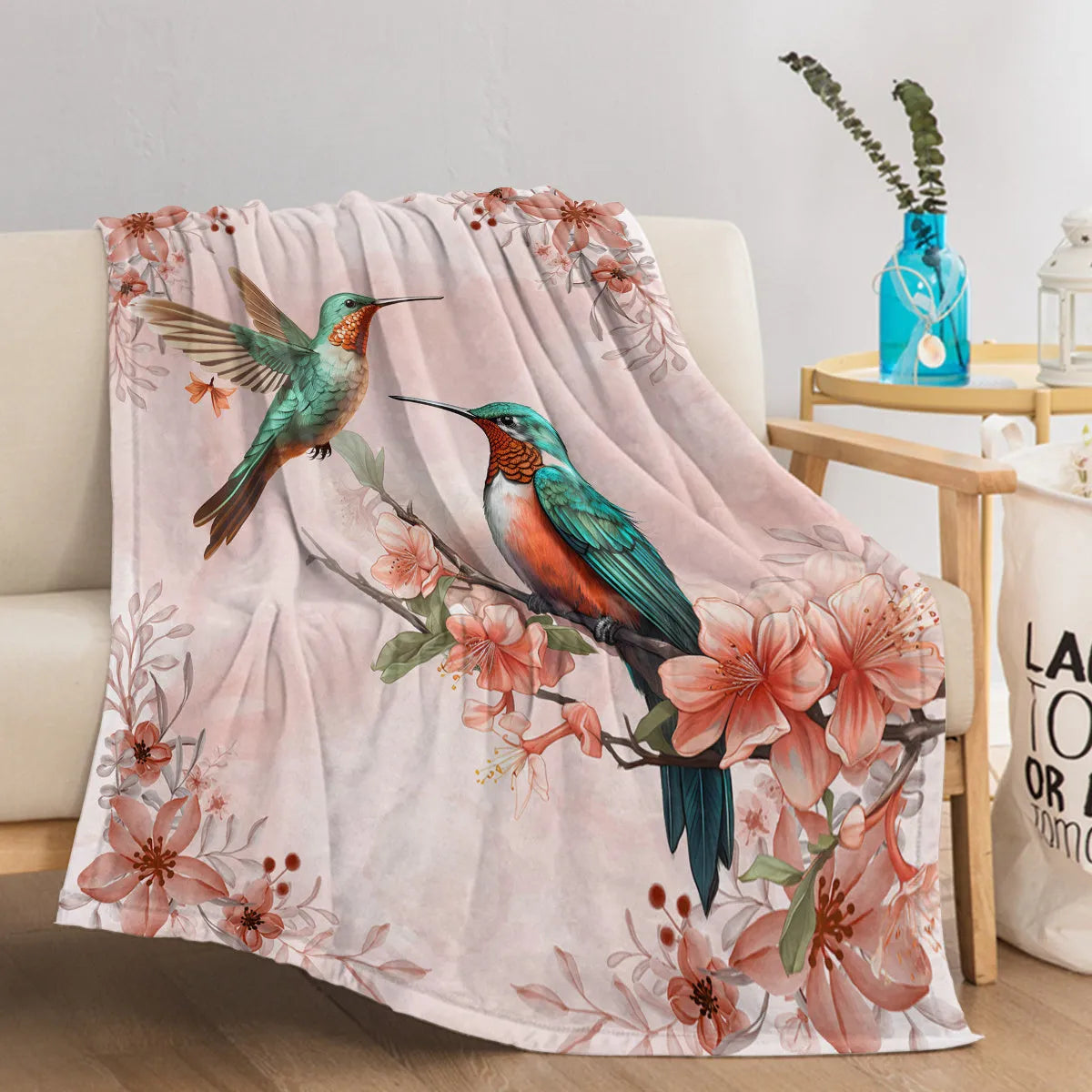 Pink hummingbird floral fleece throw blanket on sofa with floral print