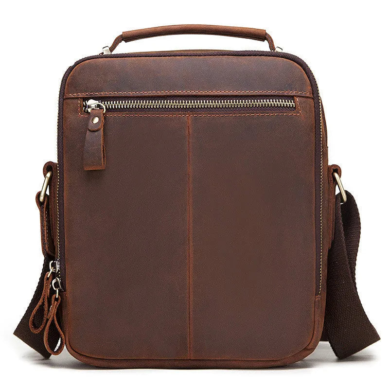 Men's brown Crazy Horse leather crossbody bag with sewing line detail on a table.