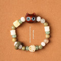 Beaded bracelet with a cube sugar cat's paw charm in guajacwood or ebony, featuring jade beads and a choice of yellow or blue eyes.