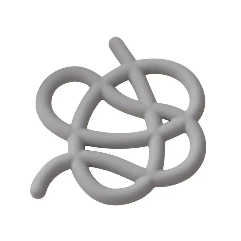 Irregular-shaped ceramic heat proof mat in grey on a wooden table next to a hot pan.