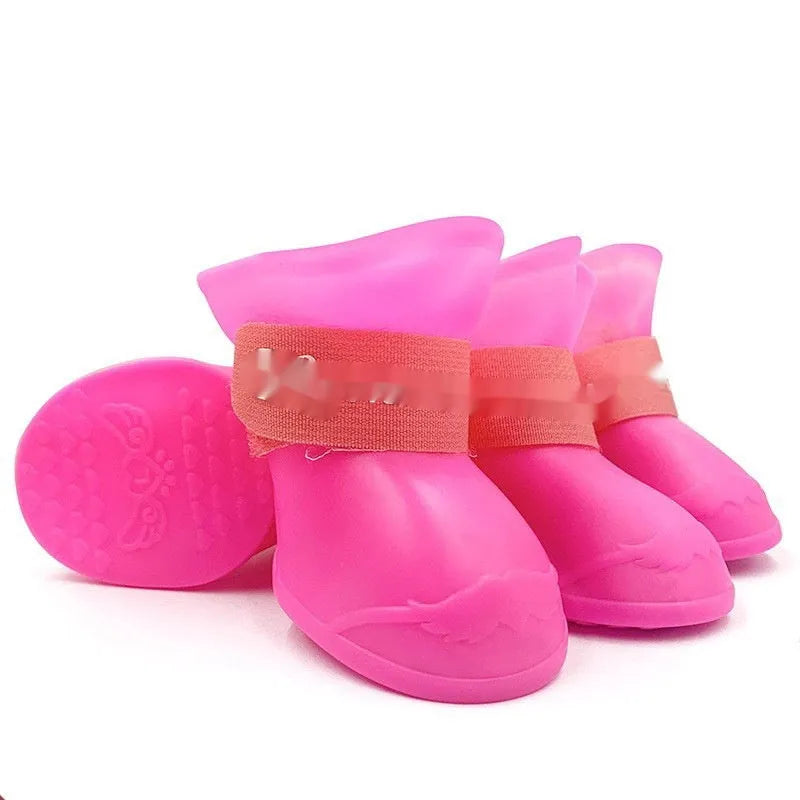 Set of four soft-soled rubber rain shoes for dogs in various colours on a wet surface.