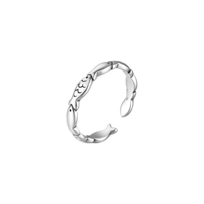 Close-up of a women's adjustable sterling silver ring with a vintage fish design on a finger.