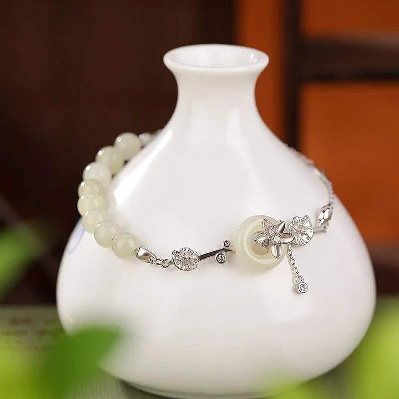 Women's 925 silver bracelet with inlaid Hetian jade centrepiece and ornate lotus peace buckle design.
