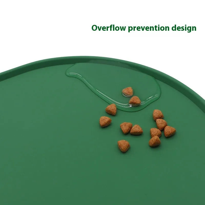 Green silicone cat feeding mat with raised edges containing dry kibble, placed on a wooden floor.