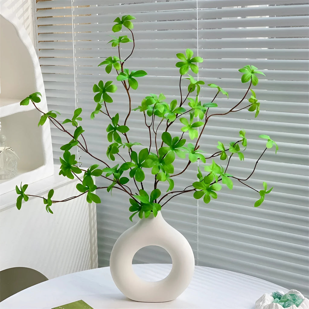 Artificial silk flower arrangement in a glass bottle vase, suitable for indoor home decor on a table
