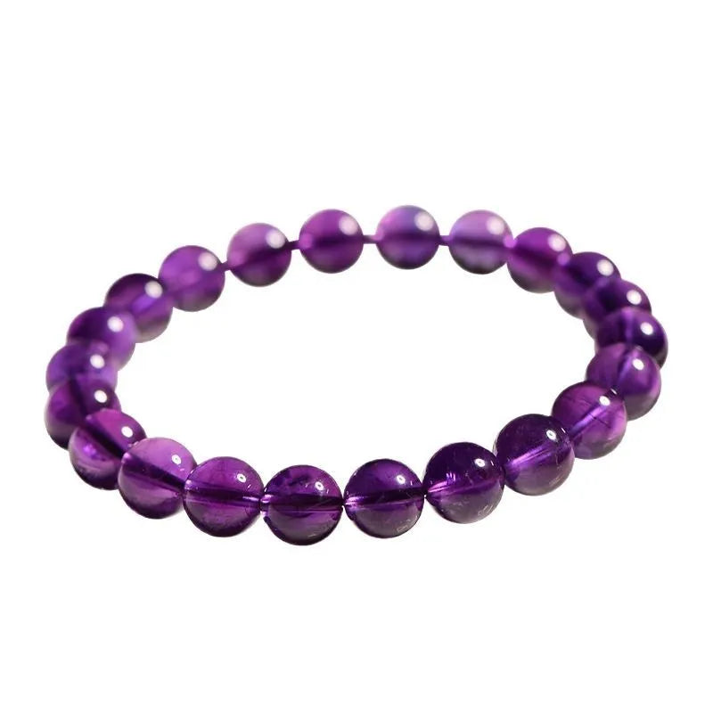 Close-up of a polished natural amethyst bead stretch bracelet on a wrist, showing deep violet colour and elasticated band.