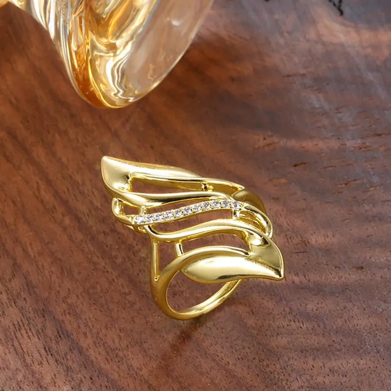 Gold coloured women's ring with an exaggerated curved design on a copper band.