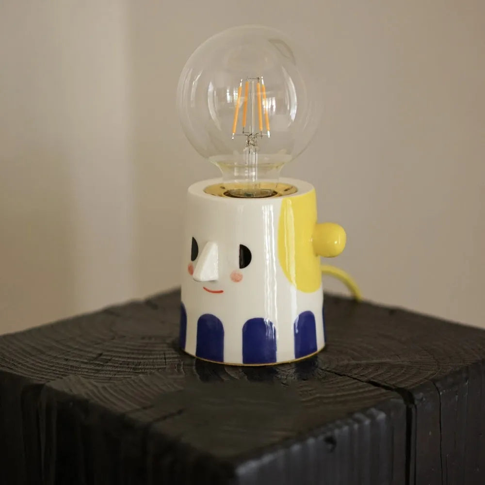 Off-white handmade ceramic table lamp with a rounded shape on a wooden surface.