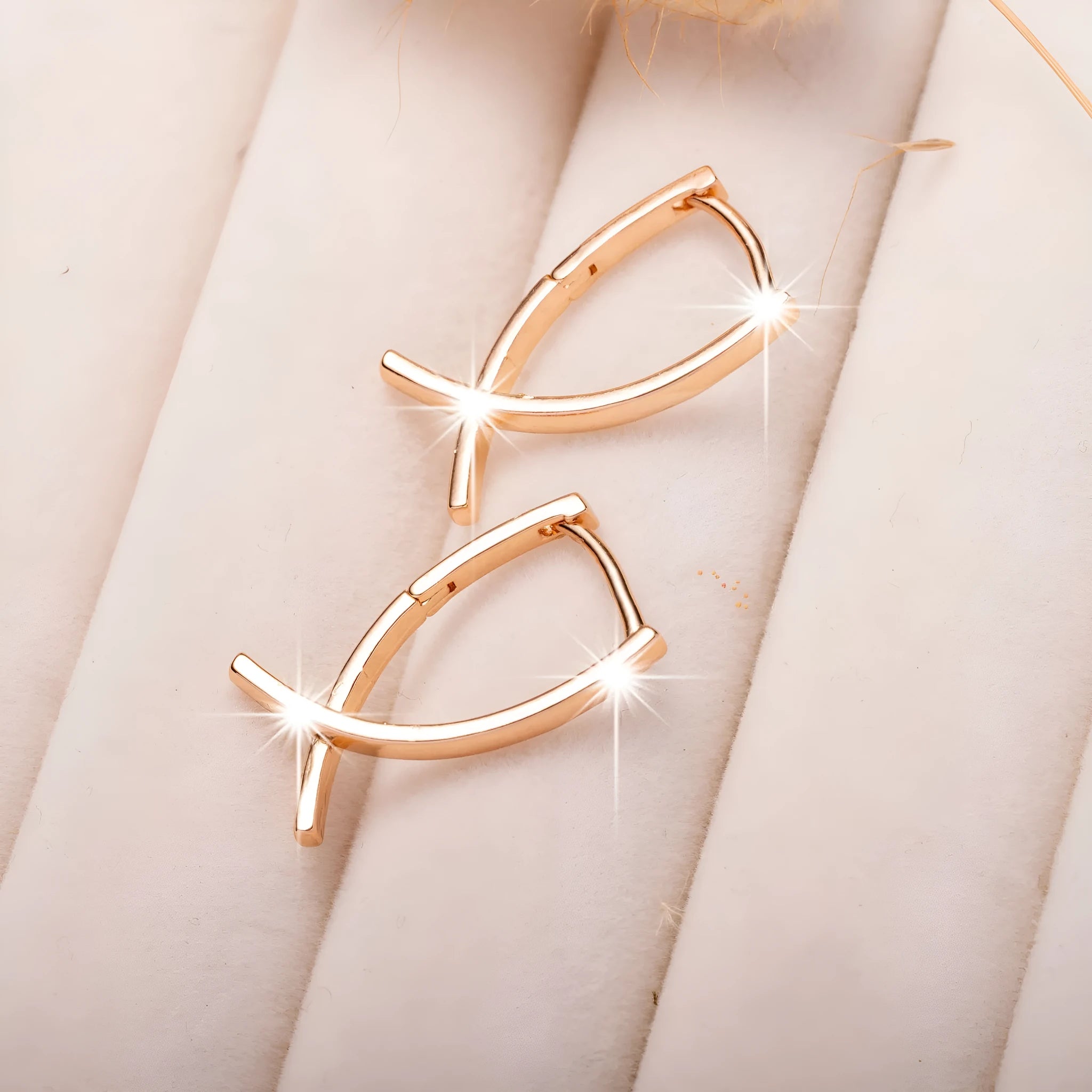 Rose gold tone cross-shaped copper earrings on a flat surface, showing polished finish and push-back clasp.