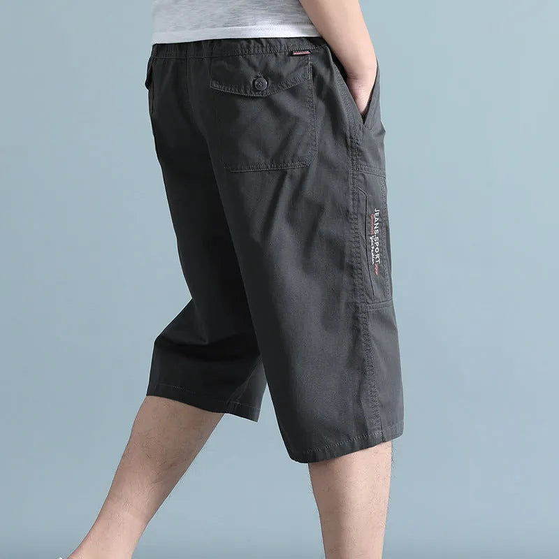 Men's loose-fit cotton sports trousers in cropped length, shown in army green colour.
