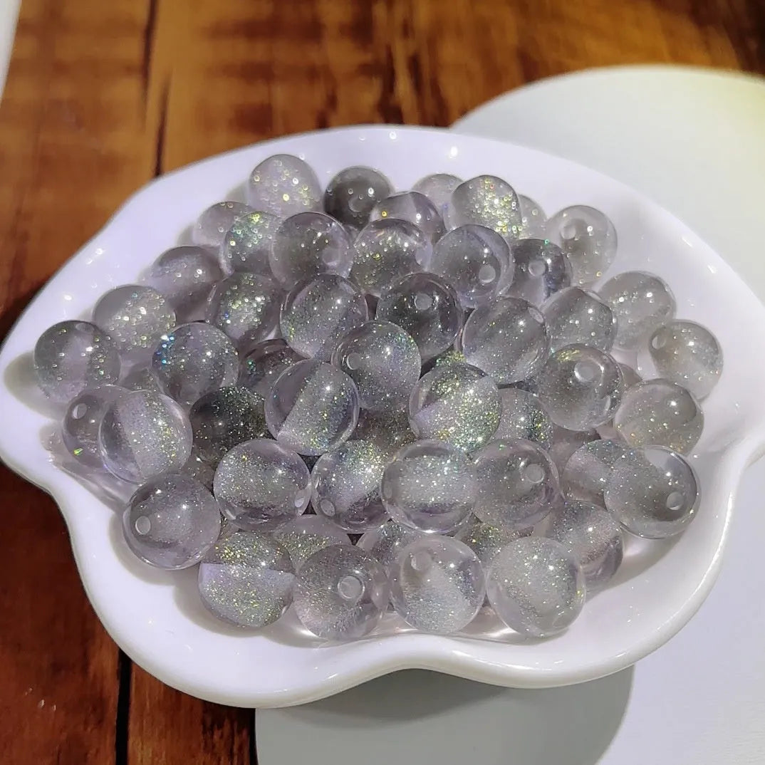 16mm round plastic scattered beads with glittering cat's eye effect in champagne colour, on a white background.