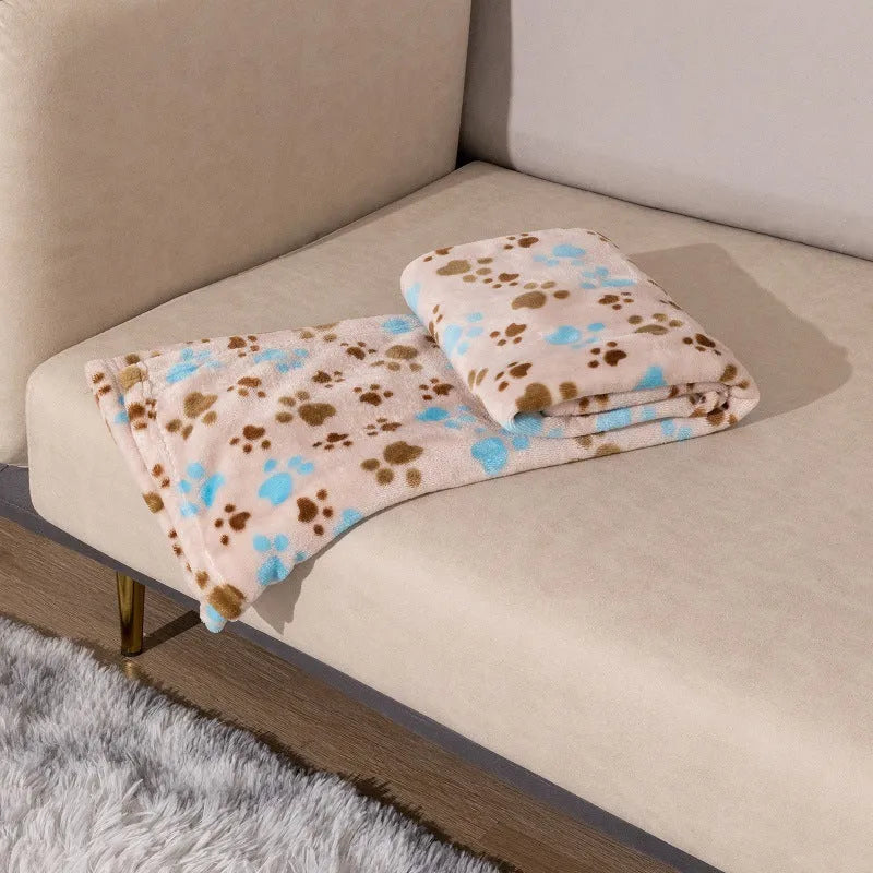 Blue cartoon dog paw print pattern on a thick double-sided flannel pet blanket laid flat.