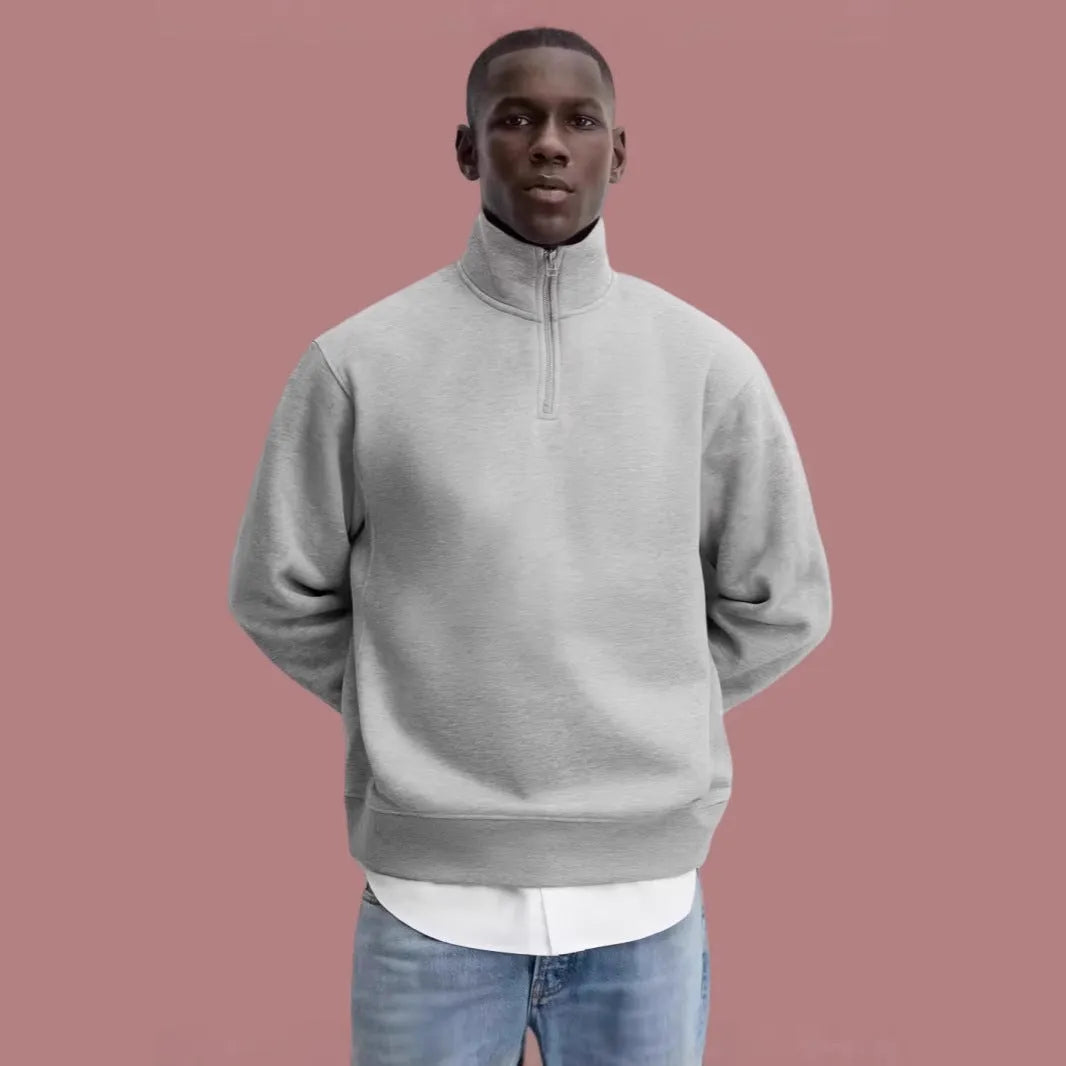 A grey half-zip stand collar cotton sweater laid flat, showing the front zip and long sleeves.