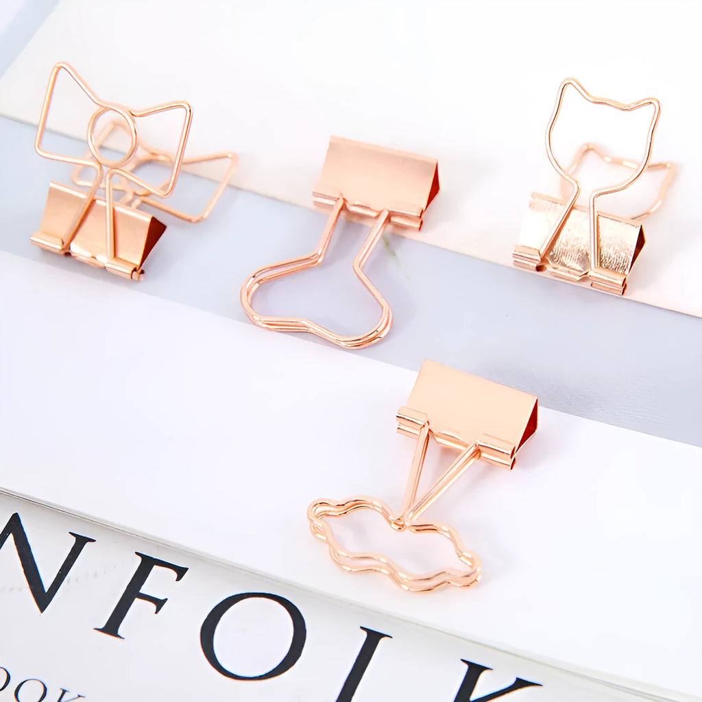 Gold metal alloy paper clip with decorative bow shape top on white background.
