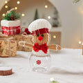 Cloth gingerbread man Christmas ornament with red and white hat design hanging on a holiday tree branch