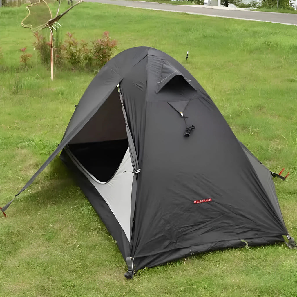 Red single-person backpacking tent with aluminium poles pitched in a forest, showing double-skin design and mesh panel.