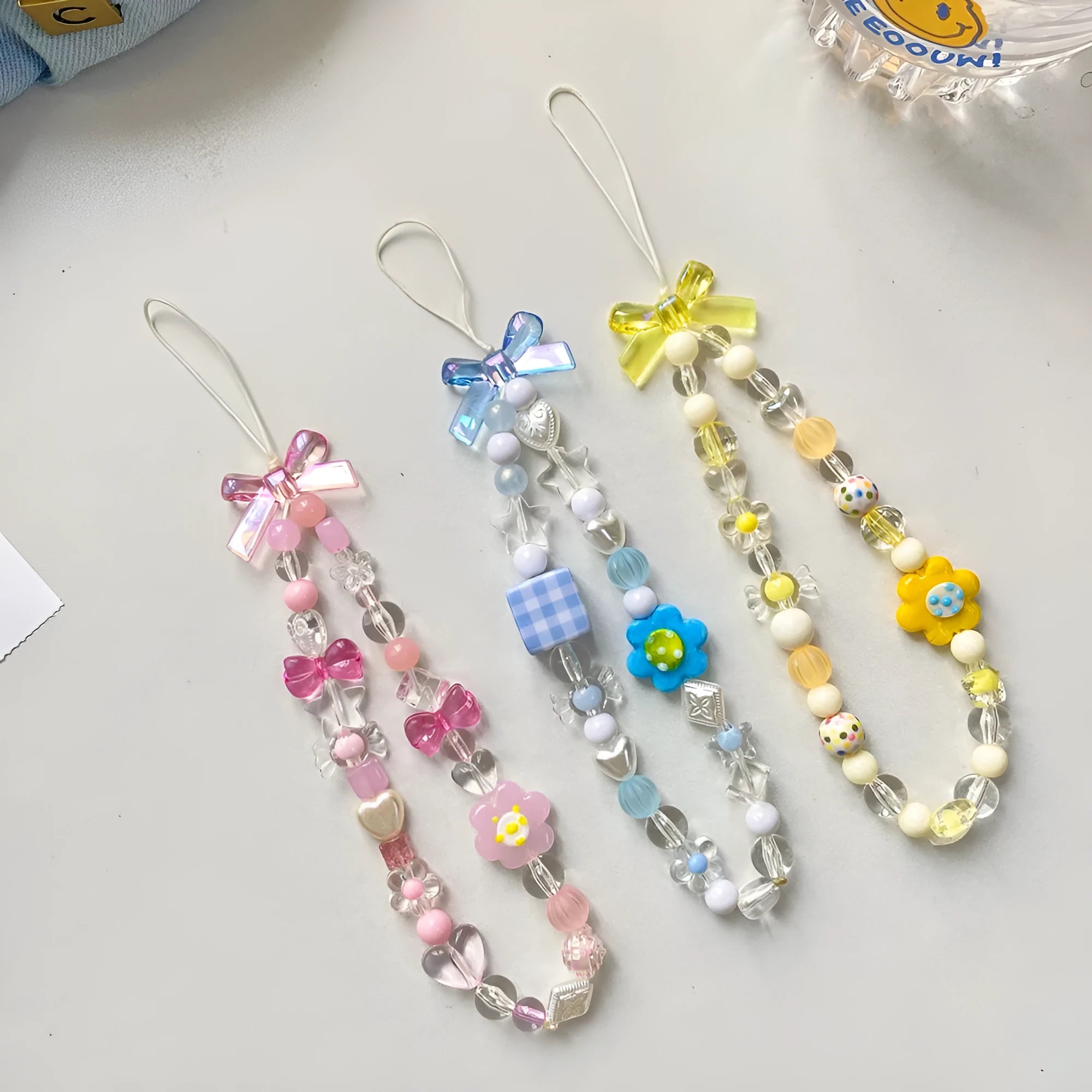 Colourful beaded floral phone lanyard in blue, pink, or yellow on a rope cord.
