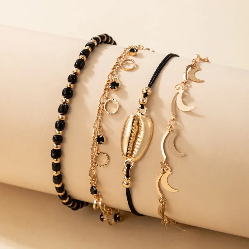 Women's gold tone alloy anklet set with hollow circles, shell beads, and black rice beads, four pieces