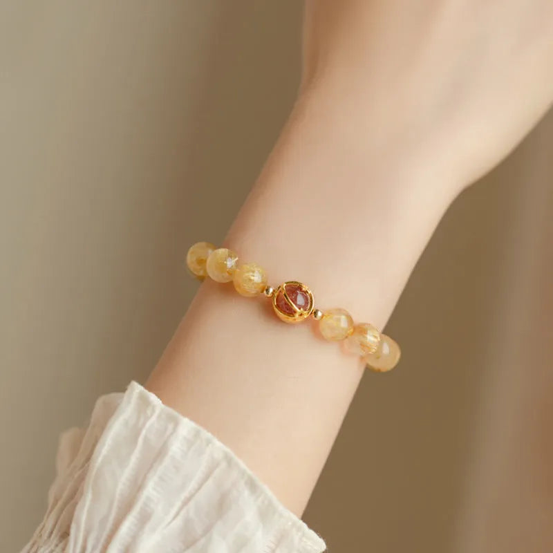 Citrine and gold rutilated quartz bracelet with diamond faceted beads on a wrist.