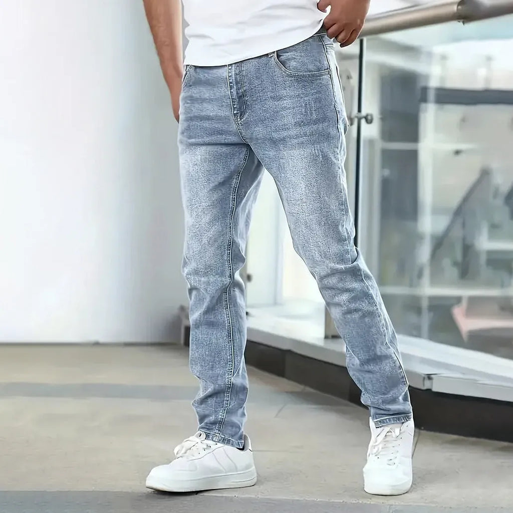 A pair of men's solid colour stretch jeans in a straight leg skinny fit, shown in dark blue.